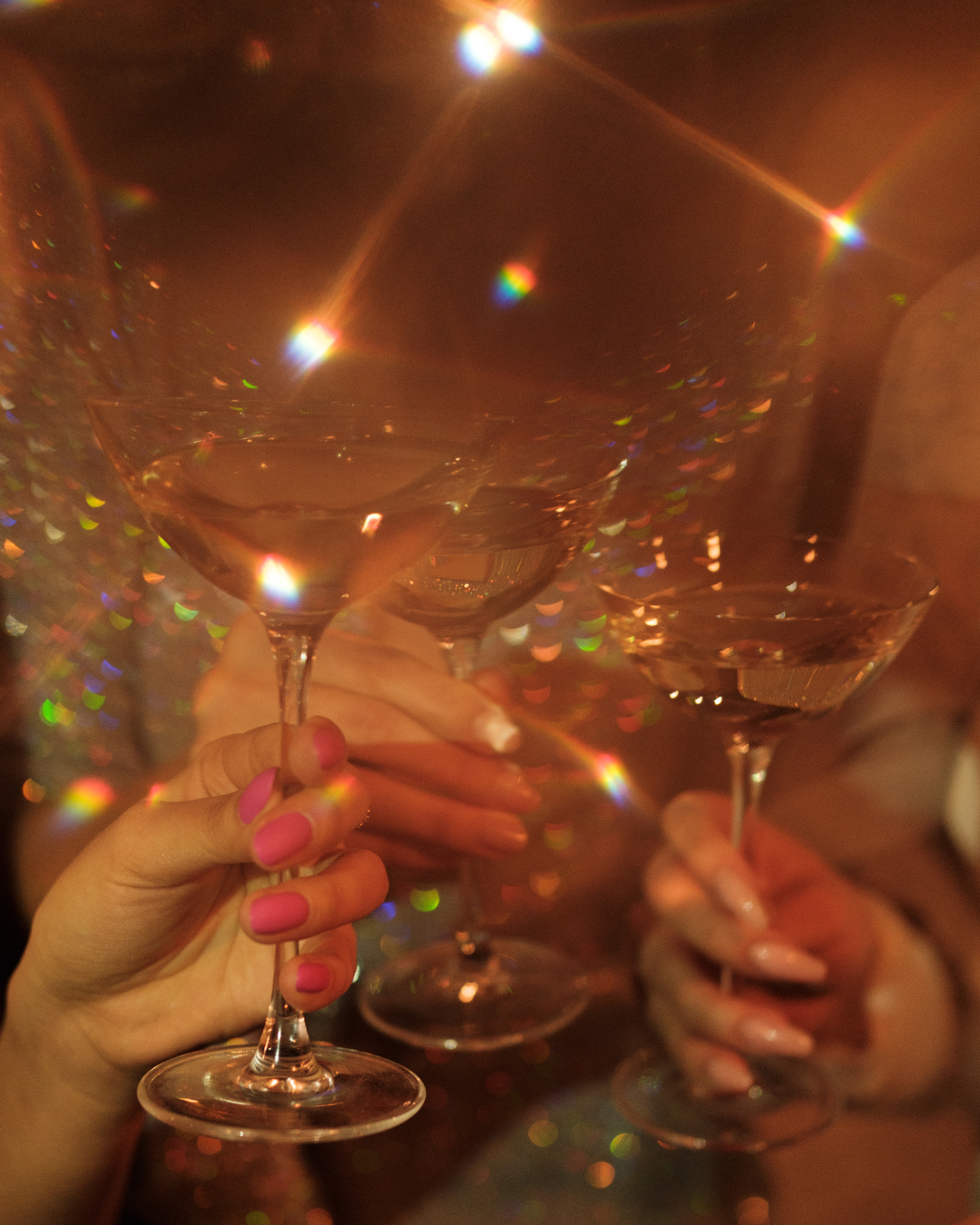 Close-up of hands holding cocktail glasses with a blurred background